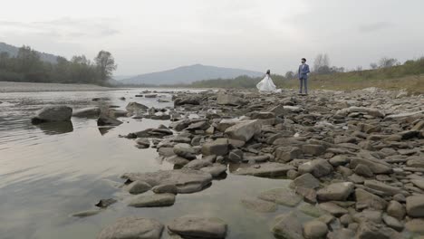 Wedding-couple-standing-near-mountain-river.-Groom-and-bride-in-love