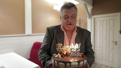 Happy-respectable-old-man-holding-cake.-Celebrating.-Blowing-birthday-candles