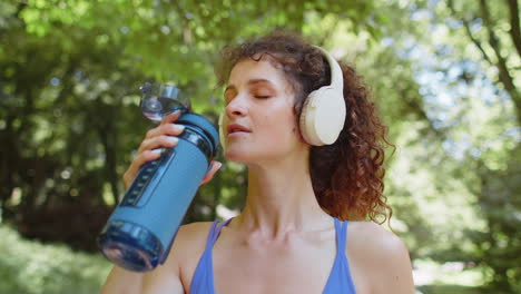 Sportlich-Fitte-Läuferin-Trinkt-Wasser-Aus-Der-Flasche-Nach-Dem-Cardio-Training-Im-Park