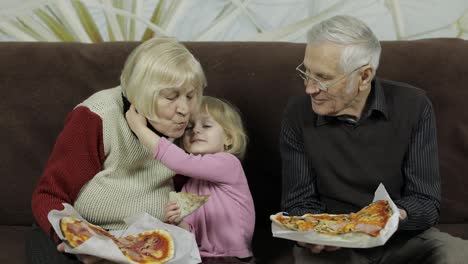 Beautiful-elderly-man-and-woman-eats-pizza-with-their-granddaughter