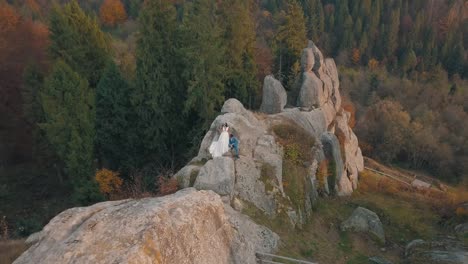 Newlyweds-stand-on-a-high-slope-of-the-mountain.-Groom-and-bride.-Arial-view