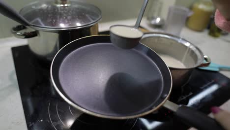 The-process-of-cooking-homemade-pancakes.-Woman-pours-pancake-dough-on-pan