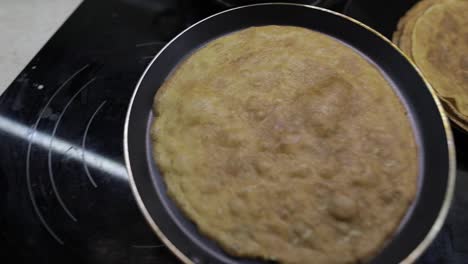 The-process-of-cooking-homemade-pancakes.-Woman-puts-pancake-from-pan-to-plate