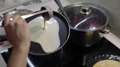 The-process-of-cooking-homemade-pancakes.-Woman-pours-pancake-dough-on-pan