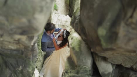 Groom-with-bride-standing-in-cave-of-mountain-hills.-Wedding-couple-in-love