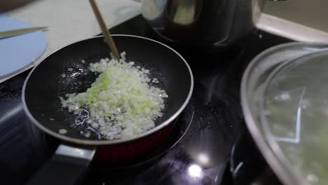 Fried-chopped-onion-in-hot-boiling-oil.-Closeup-of-frying-pan,-cooking-onion