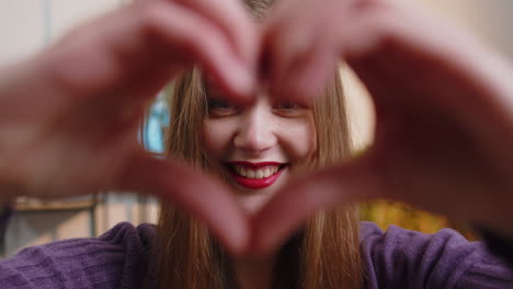 Happy-young-woman-girl-makes-symbol-of-love-showing-heart-sign-to-camera-express-romantic-feelings