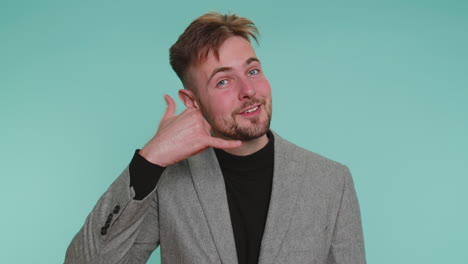 Cheerful-business-man-in-jacket-looking-at-camera-doing-phone-gesture-like-says-hey-you-call-me-back