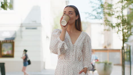 Mujer-Sonriente-Feliz-Caminando-Por-La-Calle-De-La-Ciudad-Disfrutando-De-Un-Café-Matutino,-Una-Bebida-Caliente,-Relajándose-Y-Tomando-Un-Descanso