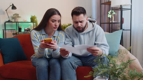 Stressed-man-woman-looking-at-unpaid-bank-debt-loan,-doing-paperwork,-planning-budget,-throws-bills