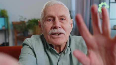 Punto-De-Vista-De-Un-Abuelo-Mayor-Haciendo-Una-Videollamada-Selfie-En-Línea,-Hablando-Y-Saludando-Con-La-Mano-Mientras-Mira-A-La-Cámara