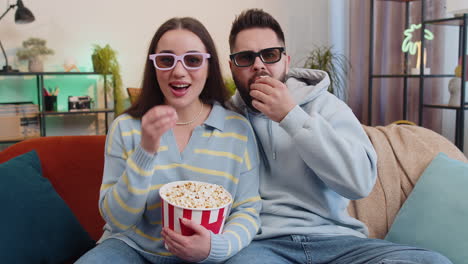 Family-man-woman-on-couch-eating-popcorn,-watching-interesting-TV-serial,-sport-game-online-at-home