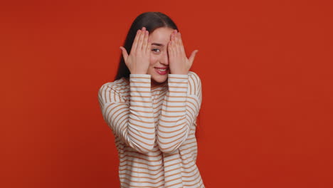 Nosy-curious-young-woman-closing-eyes-with-hand-and-spying-through-fingers,-hiding-and-peeping