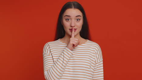 Young-woman-presses-index-finger-to-lips-makes-silence-gesture-sign-do-not-tells-secret-shh-be-quiet