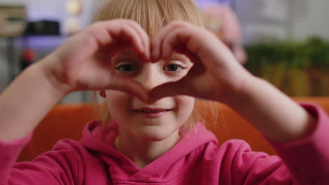 Young-child-kid-girl-makes-symbol-of-love,-showing-heart-sign-to-camera,-express-romantic-feelings