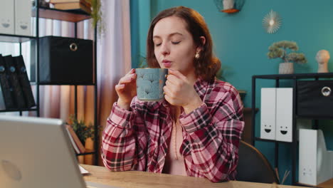 Businesswoman-working-on-laptop-computer-drinking-cup-of-warm-hot-coffee-sit-at-table-at-home-office