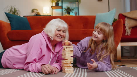 Nieta-Linda-Y-Emocionada-Jugando-Un-Juego-De-Bloques-De-Construcción-Con-Una-Abuela-Mayor-Sonriente