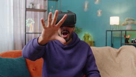 Man-using-virtual-reality-futuristic-technology-headset-to-play-simulation-3D-video-game-at-home