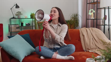 Young-woman-talking-with-megaphone,-proclaiming-news,-loudly-announcing-advertisement-at-home-room