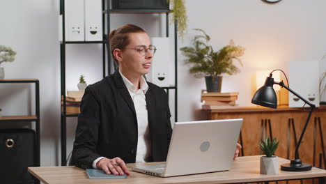 Young-father-businessman-with-laptop-having-video-call-while-little-daughter-disturbs-him-at-work