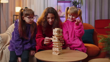 Tres-Hermanos-Niños-Niñas-Jugando-Con-Bloques-De-Juego-De-Mesa,-Construyen-Una-Torre-Con-Ladrillos-De-Madera-En-Casa