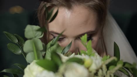 Beautiful,-lovely-bride-in-wedding-veil-at-home.-Wedding-bouquet-in-hands-from-groom-near-face