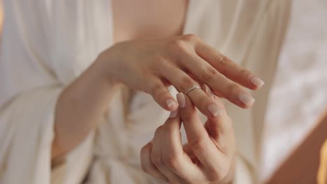 Bride-in-night-gown,-veil-wearing-engagement-ring-near-window,-Close-up,-Wedding-morning