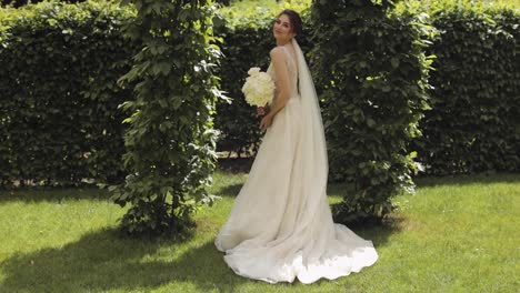 Hermosa-Novia-Elegante-Con-Vestido-De-Novia-Blanco-Y-Velo-Sosteniendo-Ramo-De-Novia-En-Las-Manos-En-El-Parque