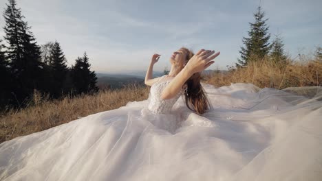 Hermosa-Y-Encantadora-Novia-Con-Vestido-De-Novia-Sentada-En-El-Césped-En-La-Ladera-De-La-Montaña