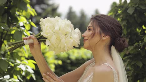 Hermosa-Novia-Elegante-Con-Vestido-De-Novia-Blanco-Y-Velo-Sosteniendo-Ramo-De-Novia-En-Las-Manos-En-El-Parque