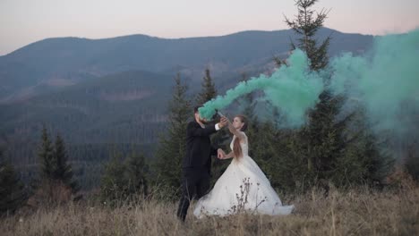 Recién-Casados.-Novio-Caucásico-Con-Novia-En-La-Ladera-De-La-Montaña-Con-Bomba-De-Humo.