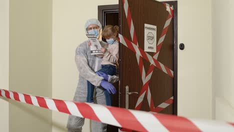 Padre-Enfermo-Con-Hija-Pequeña-Con-Mascarillas-Médicas-Abriendo-La-Puerta-De-Casa,-Cuarentena-Por-Coronavirus