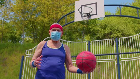 Aktiver,-Gutaussehender-Senior,-Der-Während-Des-Coronavirus-Im-Freien-Auf-Einem-Sportplatz-Basketball-Spielt