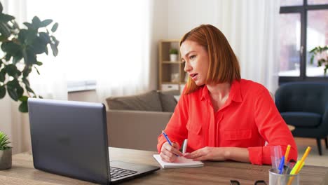 Young-woman-having-talk-video-call-on-laptop-computer-at-home..Handheld-low-angle-view-shot,-Female-freelancer-explaining-project-in-online-meeting-with-team-members-via-laptop-in-home-office.-Working-from-home,-Remote-working.