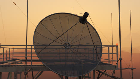 Zoom-in-on-a-microwave-antenna-placed-on-a-top-of-the-mast.--Sunset-sky-at-background.-Radio-communication-towers-3G,-4G-technology.-Cell-tower.-Network-wireless-signal-receiver-and-transmitter.-4k