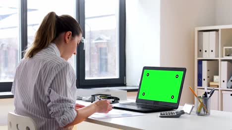 Young-Black-Woman-Sitting-at-Desk-Working-on-Laptop-Writing-in-Paper-Notebook.Confident-young-black-woman-sitting-at-desk-working-on-laptop-writing-in-paper-notebook