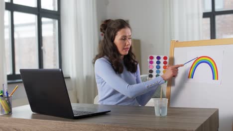 Lehrerin-Mit-Farben,-Die-Online-Kunstunterricht-Hat.-Fernunterricht,-Grundschule-Und-Unterrichtskonzept.-Lehrerin-Mit-Farben-Und-Einem-Bild-Eines-Regenbogens,-Die-Zu-Hause-Online-Kunstunterricht-Hat.