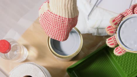 Hands-Stirring-Grey-Color-Paint-in-Can-with-Stick.repair,-painting-and-home-improvement-concept--hand-in-protective-gloves-stirring-thick-grey-color-paint-in-can-with-wooden-stick