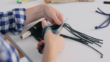 Mujer-Cortando-Cordones-De-Macramé-Con-Tijeras.-Concepto-De-Bricolaje,-Hecho-A-Mano-Y-Pasatiempo.-Mujer-Haciendo-Artesanía-De-Macramé-Y-Cortando-Cordones-Con-Tijeras-En-La-Mesa-En-Casa.