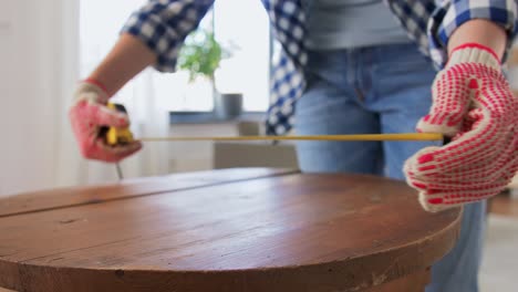 Mujer-Con-Regla-Midiendo-Mesa-Para-Renovación.-Concepto-De-Reparación,-Bricolaje-Y-Mejora-Del-Hogar.-Mujer-Con-Regla-Midiendo-Mesa-De-Madera-Redonda-Vieja-Para-Renovación-Y-Escribiendo-En-Un-Cuaderno.