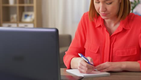 Young-woman-having-talk-video-call-on-laptop-computer-at-home..Handheld-low-angle-view-shot,-Female-freelancer-explaining-project-in-online-meeting-with-team-members-via-laptop-in-home-office.-Working-from-home,-Remote-working.