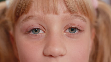 Close-up-macro-portrait-of-teen-child-kid-face-smiling,-brown-girl-eyes-looking-at-camera-blink-wink