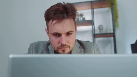 Close-up-businessman-freelancer-at-office-workplace-working-on-laptop-computer-sends-online-messages