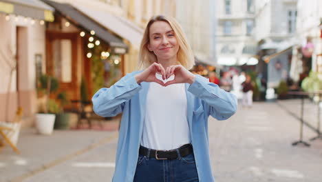 Woman-makes-symbol-of-love-showing-heart-sign-to-camera-charity-gratitude-donation-positive-feelings