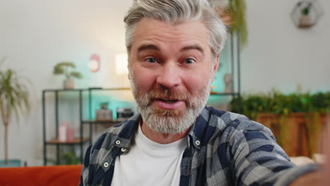 POV-portrait-of-happy-senior-man-chatting-with-friend-or-relative-on-video-call-on-smartphone