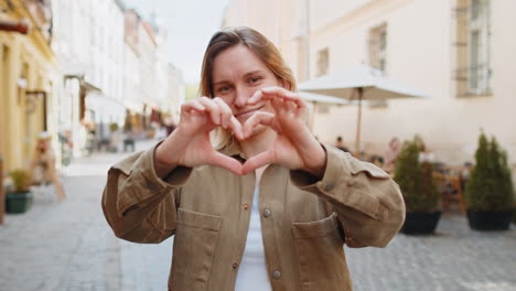 Mujer-Hace-Símbolo-De-Amor,-Mostrando-El-Signo-Del-Corazón-A-La-Cámara,-Expresando-Sentimientos-Románticos-En-La-Calle-De-La-Ciudad