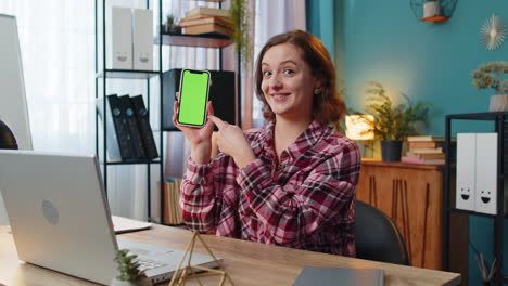 Woman-freelancer-looking-at-camera-and-showing-smartphone-with-green-screen-for-new-application