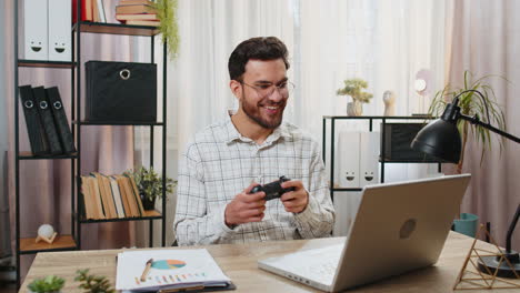 Indian-businessman-celebrating-victory-in-video-game-on-laptop-clenching-fists-spending-leisure-time