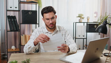 Happy-Indian-young-businessman-manager-open-envelope-letter-reading-it-bank-loan-approval-celebrate