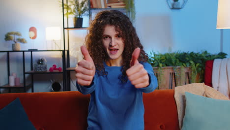 Happy-woman-showing-thumbs-up-with-hands-gesturing-like-positive-approve-looking-at-camera-at-home